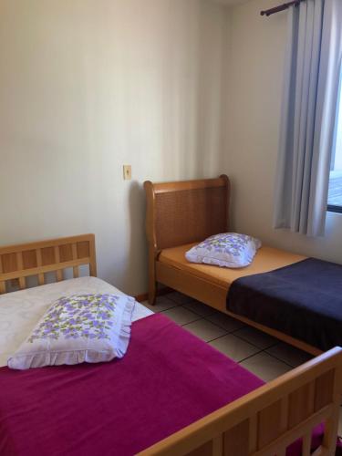 1 dormitorio con 2 camas y ventana en Apartamento Quadra Mar Itapema, en Itapema