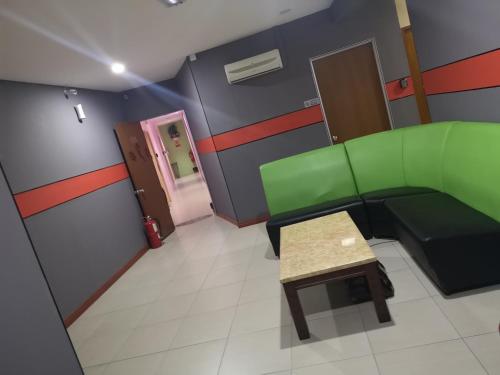 a room with a green couch and a table at Home Inn Hotel in Ipoh