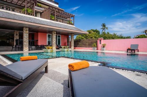 a swimming pool with two beds in front of a house at Ratana Hotel Chalong in Rawai Beach
