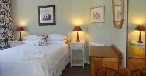 a bedroom with a bed and a desk with two lamps at Braeview Guest House in Hermanus