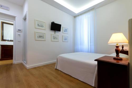 a white bedroom with a bed and a television at Casale Catania in Catania