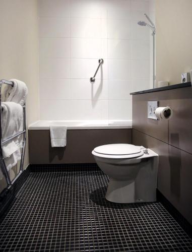 a bathroom with a toilet and a bath tub at Denham Grove in Denham