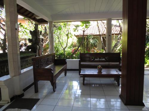a porch with two benches and a table at Swastika Bungalows in Sanur