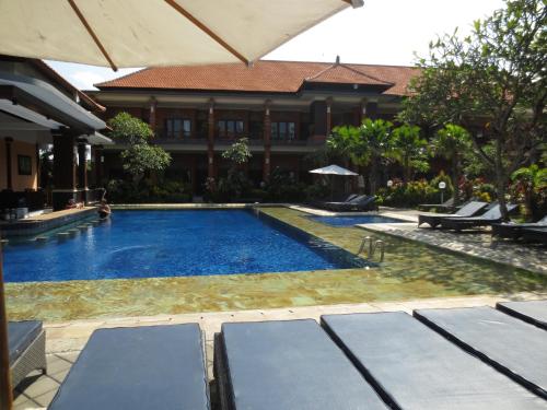 a swimming pool in front of a building at Swastika Bungalows in Sanur