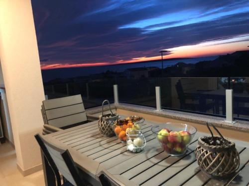a table with bowls of fruit on top of a balcony at Sunset Apartment in Mandre