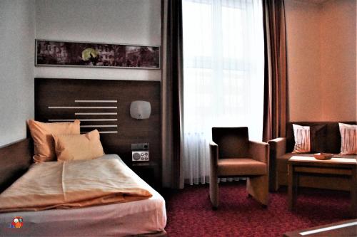 a bedroom with a bed and a chair and a window at Hotel Brühlerhöhe in Erfurt