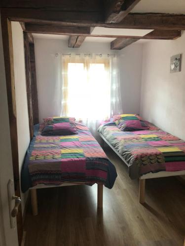 2 aparte bedden in een kamer met een raam bij Gîte Elisa et Léna in Riquewihr