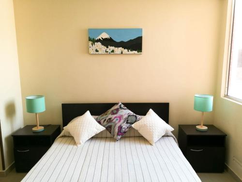 a bedroom with a bed with two lamps and a picture on the wall at Aparta hotel TOCANCIPA con Parqueadero y Wifi in Tocancipá