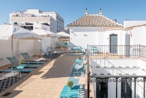 uma varanda com cadeiras e guarda-sóis num edifício em Uma Suites Parada del Marqués em Sevilha