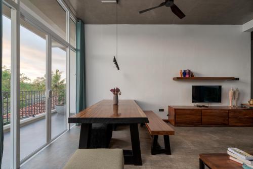a living room with a wooden table and a balcony at Hikka Hill Loft in Hikkaduwa