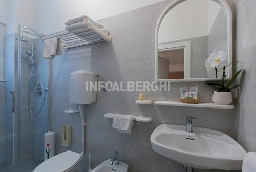 a bathroom with a sink toilet and a mirror at Hotel Katia in Cesenatico