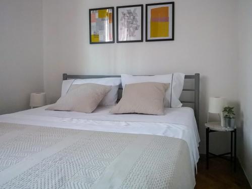 ein Bett mit weißen Laken und Kissen in einem Schlafzimmer in der Unterkunft Apartman Oleander in Split