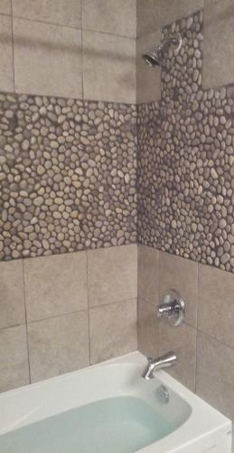 a bathroom with a bath tub with a stone wall at Riverbend Guest House in Chilliwack