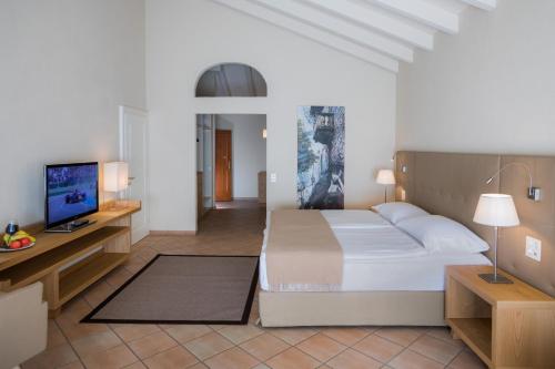a bedroom with a bed and a flat screen tv at Parkhotel Delta, Wellbeing Resort in Ascona