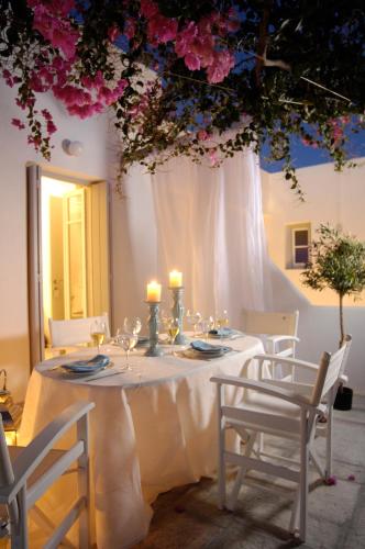a table with white chairs and pink flowers on it at Kapetan Tasos Suites in Pollonia