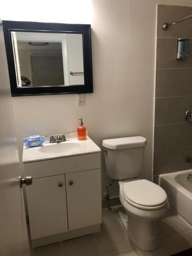 a bathroom with a toilet and a sink and a mirror at Close to Everything Miami in Miami