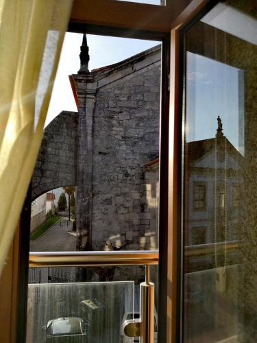 a window with a view of a brick building at Isabel do Couto - casa de charme in Castro Daire