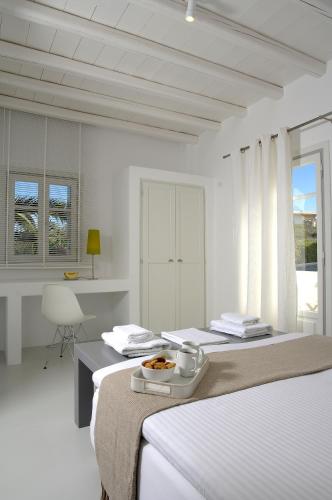 a white bedroom with two beds and a desk at Kapetan Tasos Suites in Pollonia