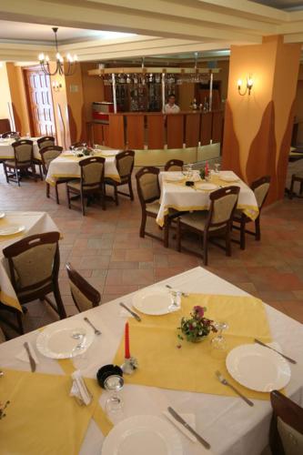 a dining room with tables and chairs with white tablecloths at Hotel Amadeo in Iaşi