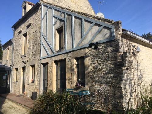 uma antiga casa de pedra com uma porta de madeira em Le mas Normand em Ver-sur-Mer