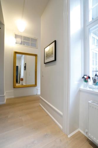 a living room with a mirror and a white wall at Camillas Holiday home Copenhagen City Centre in Copenhagen