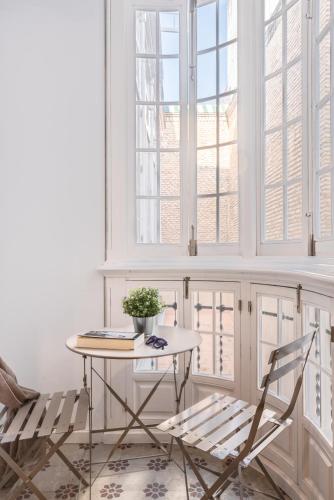 a table and a chair in a room with windows at Uma Suites Parada del Marqués in Seville
