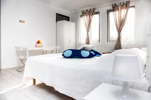 a white bedroom with a large white bed with blue pillows at Alex Residence in Otopeni