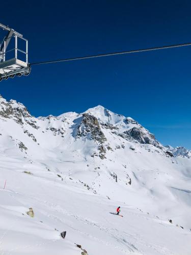 a person skiing down a snow covered mountain with a ski lift at Hotel Elite House in Mestia