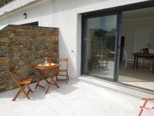eine Terrasse mit einem Tisch und Stühlen neben einer Steinmauer in der Unterkunft Appartement vue sur mer in Santa-Maria-di-Lota