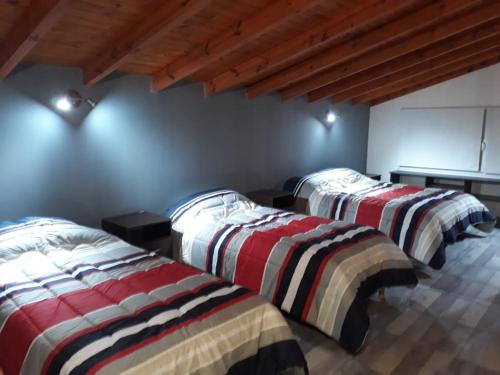 two beds in a room with wooden ceilings at La Lomada in Villa Pehuenia