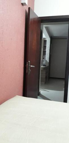 a open door to a room with a bed and a hallway at Residencial Franca Garopaba in Garopaba