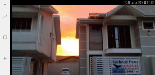 a group of houses with the sunset in the background at Residencial Franca Garopaba in Garopaba