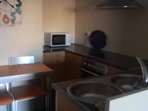eine Küche mit einer Spüle und einer Mikrowelle in der Unterkunft Se Alquila Piso Nuevo C/Garaje Céntrico en Sanxenxo in Sanxenxo
