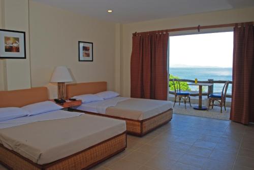 スリガオにあるAlmont Beach Resortのベッド2台とバルコニーが備わるホテルルームです。
