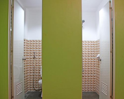 baño con pared verde y 2 espejos en Antwet Backpacker's Inn & Rooftop Bar en Dumaguete