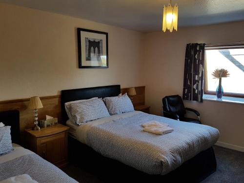 a bedroom with two beds and a chair and a window at Alba Guest House in Aberdeen