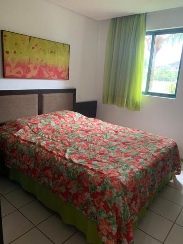 1 Schlafzimmer mit einem Bett mit Blumenbettdecke in der Unterkunft Marulhos Resort Flat E205 in Porto De Galinhas