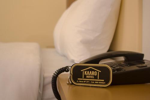a phone sitting on a table next to a bed at Kaaro Hotel Puno in Puno