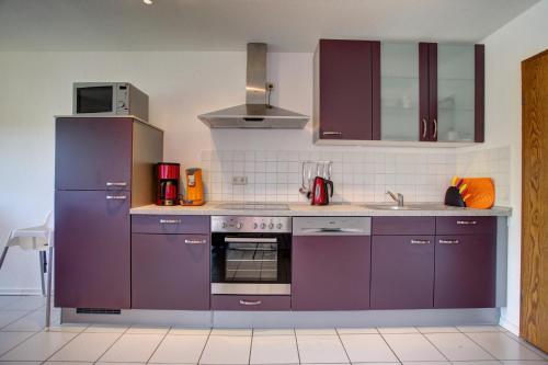 a kitchen with purple cabinets and a sink at Ferienwohnung Seeblick in Schalkenmehren