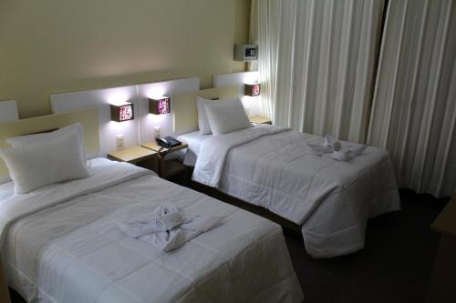 two beds in a hotel room with white sheets at Kaaro Hotel Puno in Puno