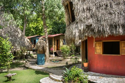 a house with a thatched roof and a yard at Alice Guesthouse in El Remate