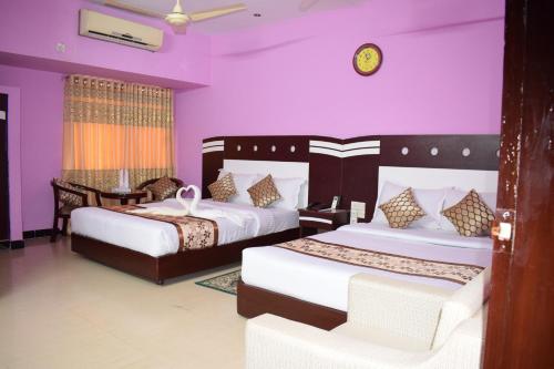 two beds in a room with purple walls at Hotel Regal Palace in Cox's Bazar
