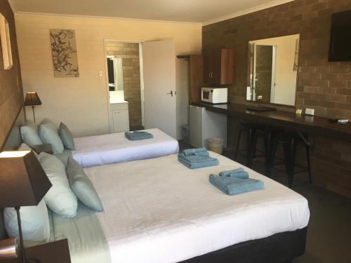 a hotel room with two beds and a kitchen at Camellia Motel in Narrandera