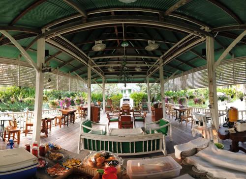 a restaurant with tables and chairs and a green roof at Baan Luang Harn in Phra Nakhon Si Ayutthaya