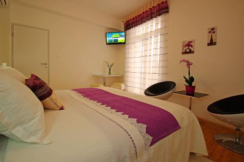 a bedroom with a bed with two chairs and a television at B&B Vela Luka in Vela Luka