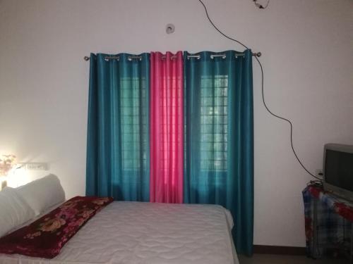 a bed with colorful curtains in a bedroom at Takashi Homestay North Paravur Near Muziris in North Paravur