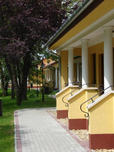a building with columns and a walkway in a park at Geréby Kúria Hotel és Lovasudvar in Lajosmizse