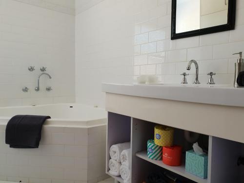 a bathroom with a sink and a tub and a sink at Salty Eyre Glenelg in Glenelg