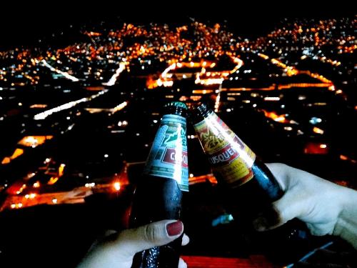 two people holding beer bottles looking at a city at Casa Mirador guesthouse in Cusco