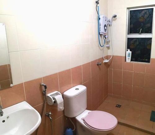 W łazience znajduje się różowa toaleta i umywalka. w obiekcie Izzanial Homestay w mieście Sandakan